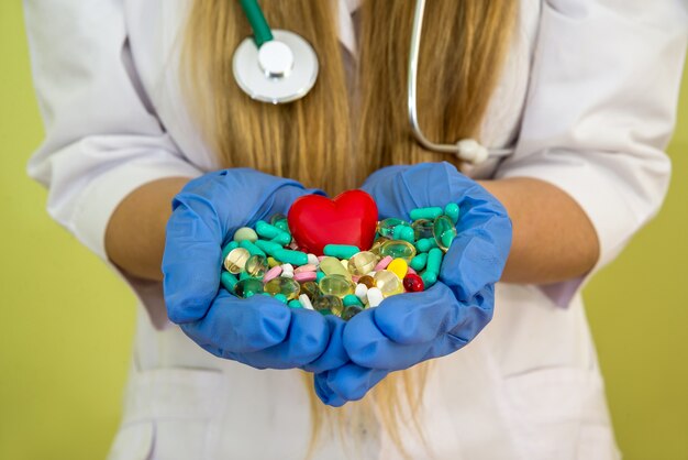 Les mains du docteur tiennent différentes pilules isolées sur un vert