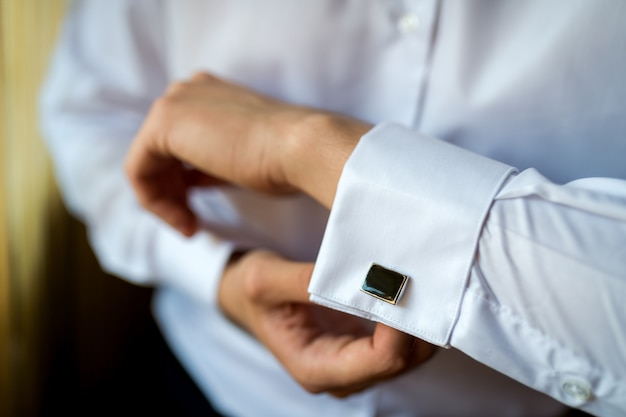 Mains du marié mariage boutonner sa chemise blanche.