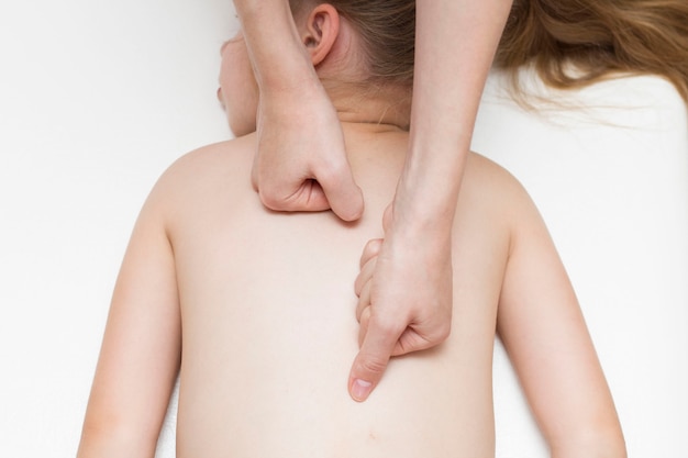 Les mains du masseur font un massage du dos pour une fille d'âge primaire. Colonne vertébrale. Mal de dos chez les enfants d'âge scolaire.