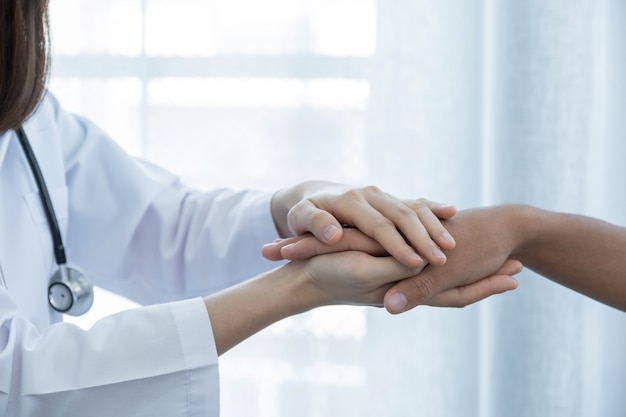 Les mains du médecin tenant la main du patient pour l'encouragement et ont expliqué les résultats de l'examen de santé.
