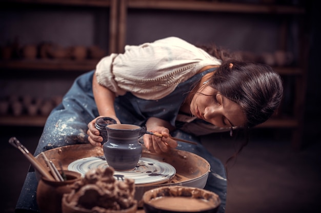 Les mains du potier font un pot en argile.