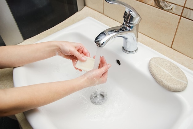 A Les mains avec du savon sont lavées sous le robinet avec de l'eau Nettoyer de l'infection, de la saleté et du virus