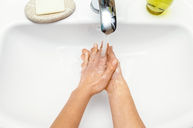 A Les mains avec du savon sont lavées sous le robinet avec de l'eau. Nettoyer de l'infection, de la saleté et des virus. À la maison ou au bureau des ablutions de l'hôpital.
