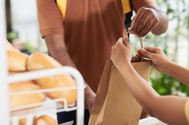 Mains du travailleur du service de livraison prenant le colis avec commande au café