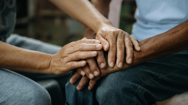 Mains du vieil homme et une main de femme sur la table en bois