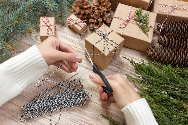 Mains emballant un cadeau sur une table en bois.