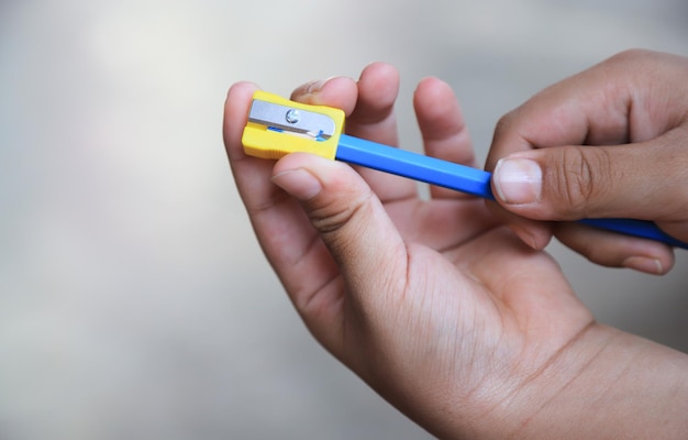Mains d'enfant à l'aide d'un taille-crayon dans la salle de l'école pour l'activité d'apprentissage