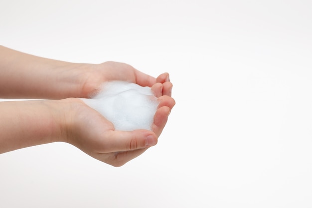 Mains d'enfant sur blanc en mousse blanche de savon antibactérien