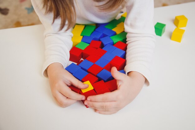 Les mains de l'enfant avec des cubes colorés sur le tableau blanc. Enfant jouant à la table. Développement précoce d'un concept d'enfant.
