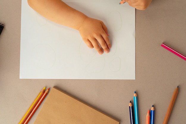 Les mains de l'enfant écrit dans un cahier ouvert, vue du dessus, copiez l'espace