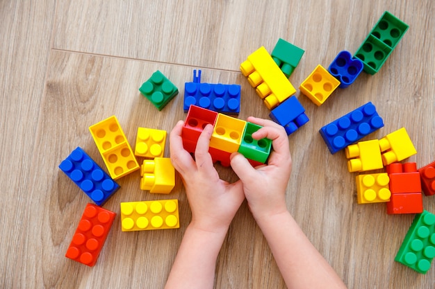 Mains de l'enfant jouant avec des blocs de jouets colorés. concepteur de jeux pour enfants.