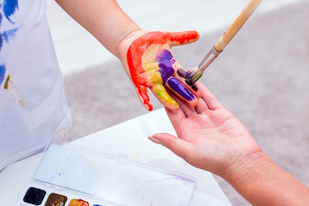 Mains d'un enfant peint avec des couleurs vives.