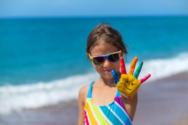 Mains d'enfant peintes avec des peintures sur la mer. Mise au point sélective. Enfant.