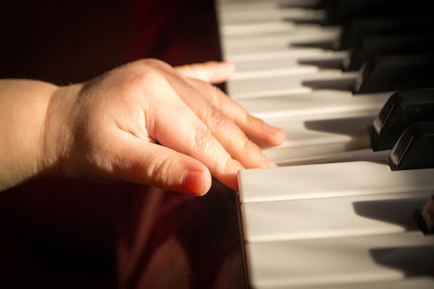 Les mains de l'enfant sur le piano.