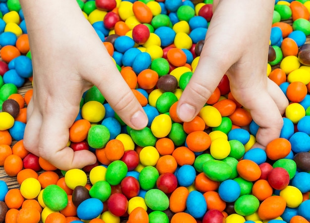 Les mains de l'enfant prenant des bonbons ronds sucrés de la table