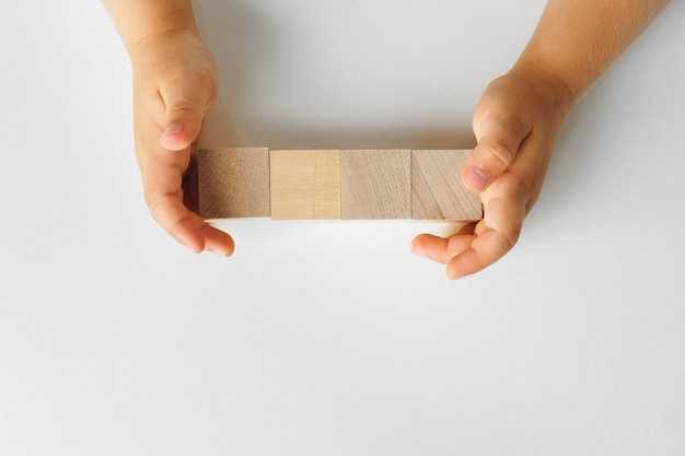 Mains d'un enfant avec quatre blocs de bois