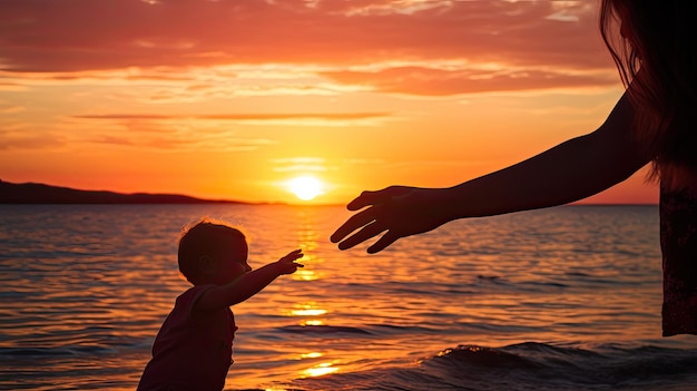 Les mains d'un enfant et de sa mère se touchent au coucher du soleil au bord de la mer