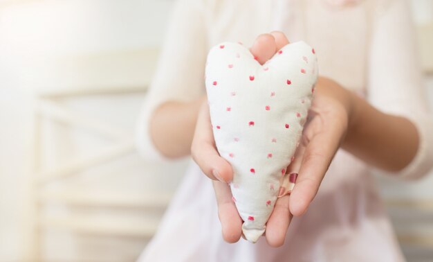 Mains d'enfant tenant un coeur de coton. La Saint-Valentin .