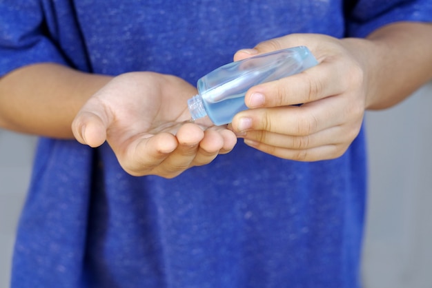 Photo mains d'enfant verser des gouttelettes appliquer un désinfectant gel d'alcool bouteille portable pour une hygiène propre prévenir les virus