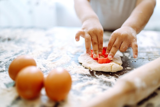 Mains d'enfants découpant des formes et faisant des biscuits Faire des biscuits pour les décorations de Noël