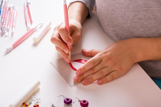 Les mains des enfants découpent un détail en argile polymère avec un outil Fait main et loisirs