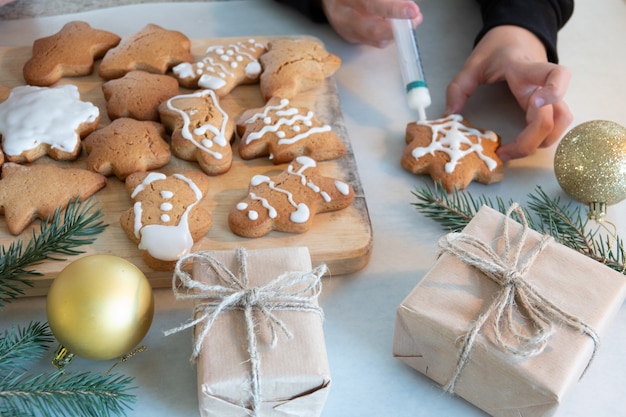 Les mains des enfants font des biscuits au pain d'épice du Nouvel An sur une table en bois. Faire des biscuits avec un emporte-pièce. Concept de nouvel an et de Noël.