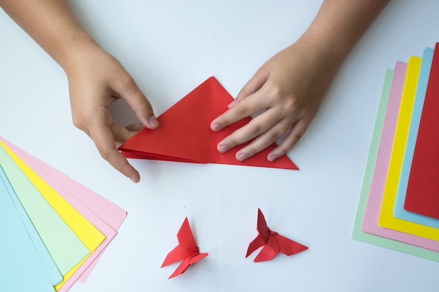 Les mains des enfants font un papillon origami.