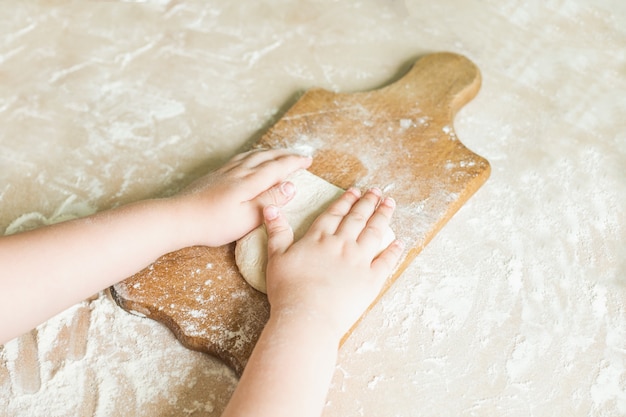 Les mains des enfants font de la pâte