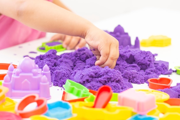 Les mains des enfants jouent au sable cinétique en quarantaine. sable violet sur une table blanche. pandémie de Coronavirus