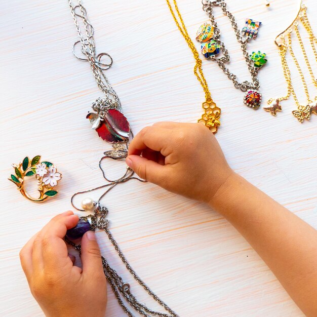 Photo les mains des enfants jouent avec des bijoux d'été légers sur fond blanc concept de bonheur pour femmes