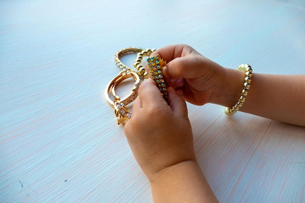 Les mains des enfants jouent avec des bijoux en or et de la bijouterie sur fond blanc concept de bonheur pour femmes