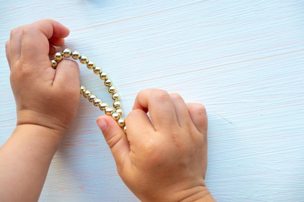 Les mains des enfants jouent avec des bijoux en or et de la bijouterie sur fond blanc concept de bonheur pour femmes