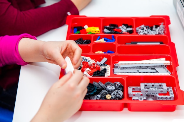 Les mains des enfants jouent avec des blocs lego colorés sur table blanche