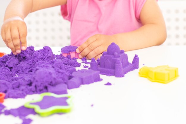 Les mains des enfants jouent du sable cinétique en quarantaine. sable violet sur un tableau blanc. pandémie de Coronavirus