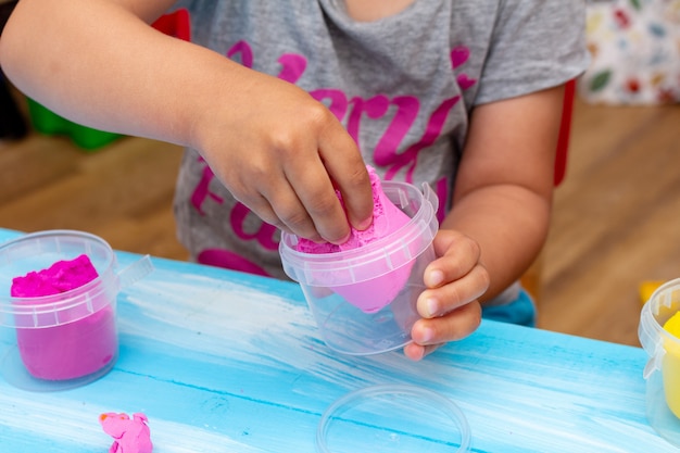 Les mains des enfants moulent la pâte colorée en gros plan. Concept de l'éducation des bébés de la petite enfance