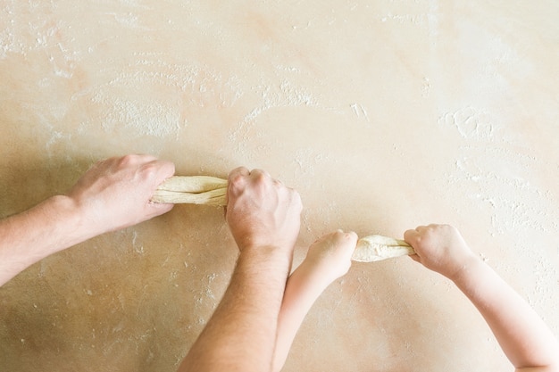 Les mains des enfants et des papas font de la pâte crue