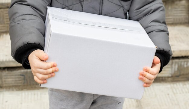 mains d'enfants tenant une boîte blanche