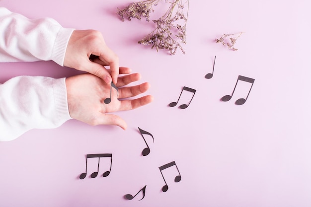 Les mains des enfants touchent des notes de papier et des notes autour d'un fond rose Éducation musicale Vue de dessus