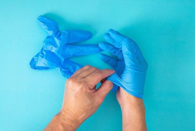 Les mains enlèvent le gant sur le fond bleu