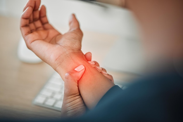 Mains entreprise ou personne avec douleur au poignet tout en travaillant sur un ordinateur dans un lieu de travail de bureau avec une lueur rouge ou une blessure Syndrome du tunnel carpien blessé ou gros plan du travailleur blessé avec inconfort crampe du bras