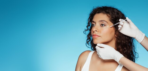 Photo mains d'une esthéticienne faisant une injection pour une heureuse femme caucasienne millénaire