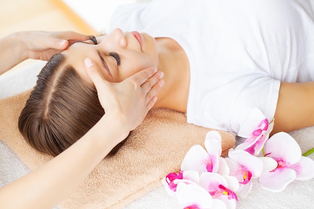 Mains d'esthéticienne faisant un massage facial rajeunissant relaxant manuel pour femme dans un salon de beauté