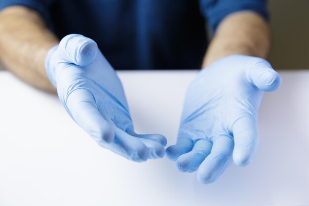 Photo des mains expressives d'un médecin ou d'une infirmière en gants sur une table blanche