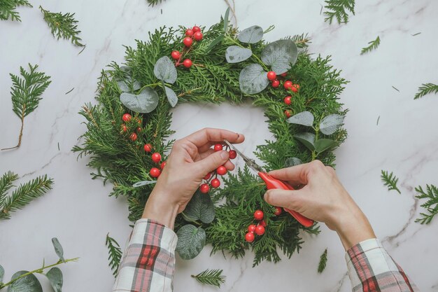 Mains faisant une couronne de Noël étape par étape