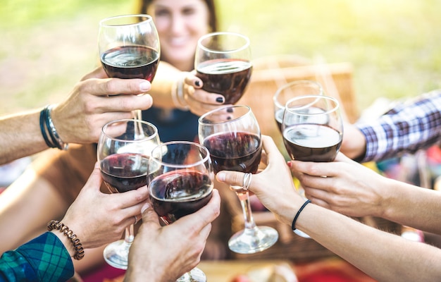 Mains faisant griller du vin rouge et des amis s'amusant à applaudir à l'expérience de dégustation