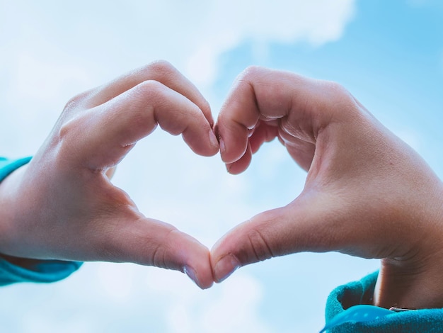 mains faisant le symbole du coeur sur le ciel