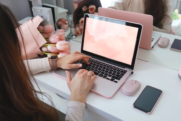 Mains Féminines à L'aide D'un Ordinateur Portable. Bureau Féminin Espace De Travail Bureau à Domicile Maquette Avec Ordinateur Portable, Bouquet De Fleurs De Tulipes Roses, Smartphone Et Accessoires Roses.