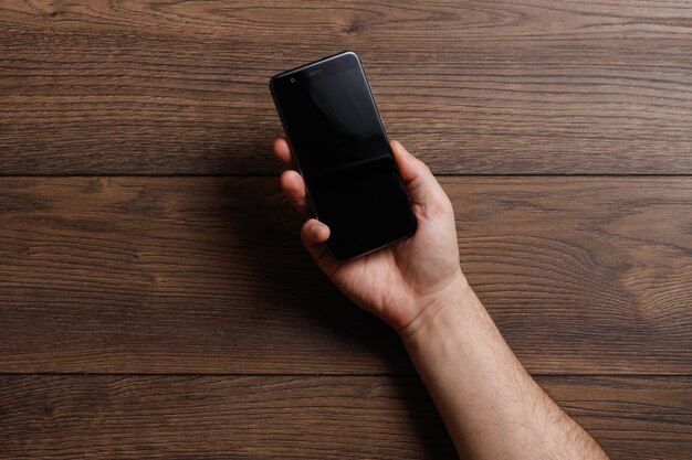 Photo mains féminines à l'aide d'un smartphone sur une table en bois