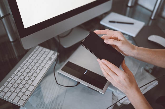 Mains Féminines à L'aide De Téléphone Intelligent En Milieu De Travail Intérieur, Femme D'affaires Indépendante à L'aide De Téléphone Portable Au Bureau, Travaillant à Domicile à L'aide D'un Téléphone Intelligent Et D'un Ordinateur Portable. Quarantaine Des Travailleurs Distants