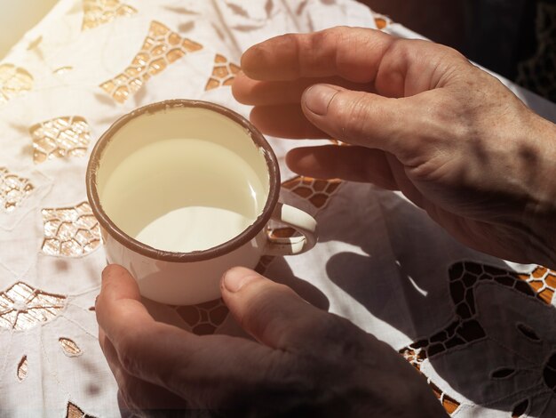 Mains féminines après un travail acharné prenant une tasse blanche en métal avec de l'eau